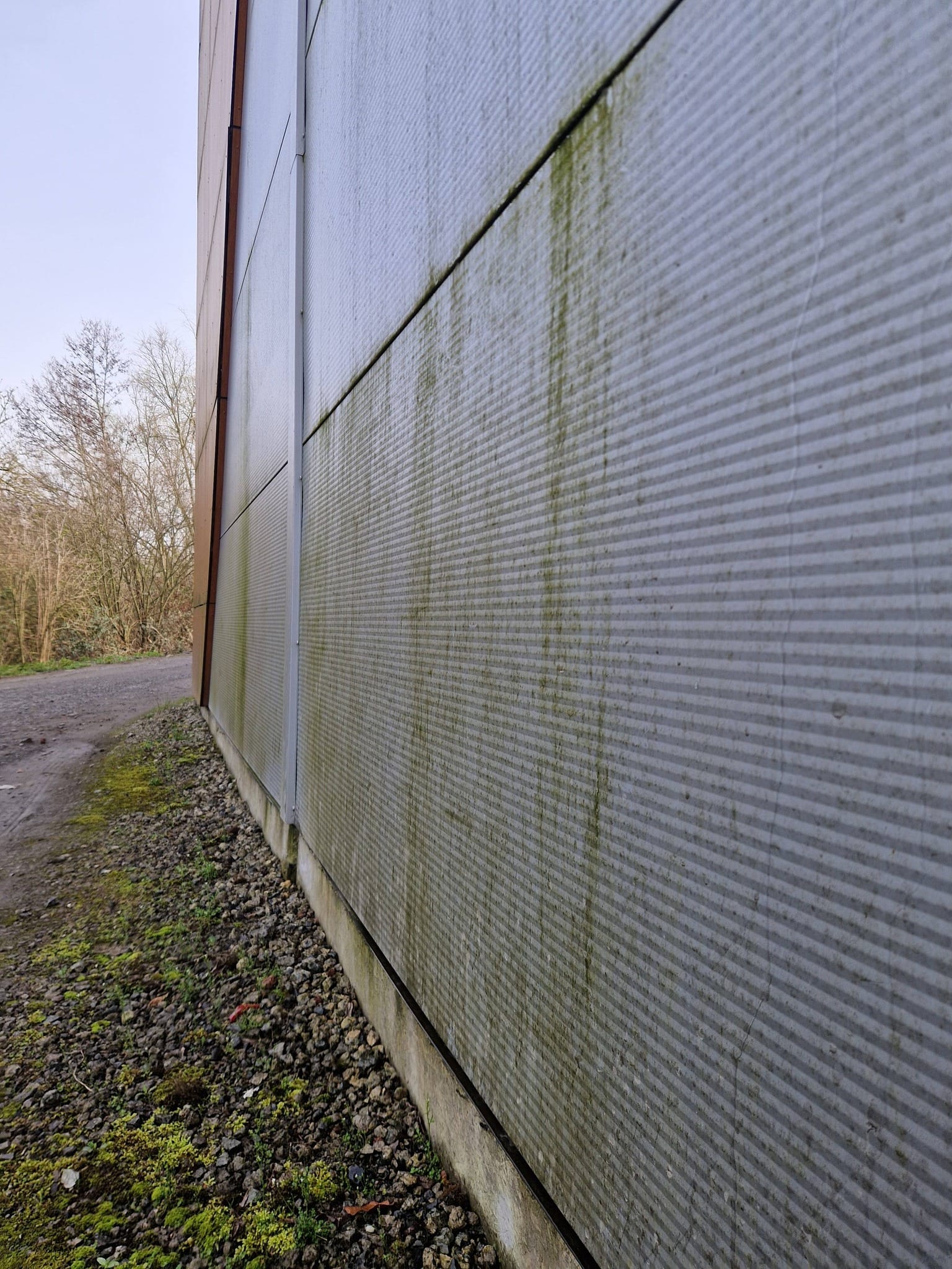 Bardage et mur de façade d'un grand magasin encrassés par la pollution avant nettoyage.
